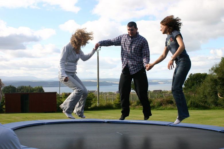 Neil and sisters bouncing on trampoline